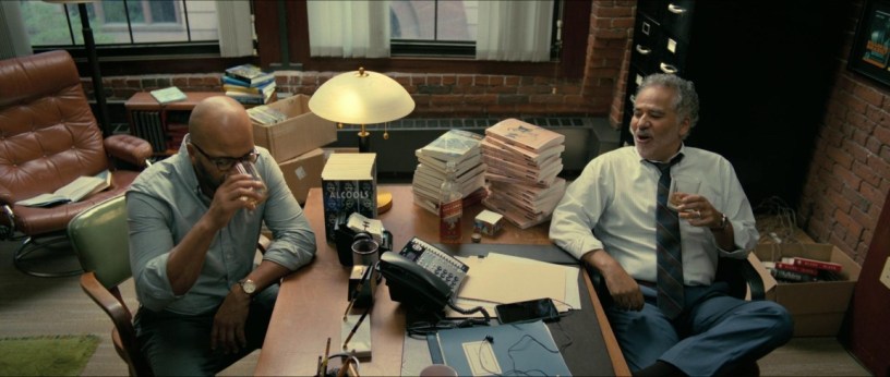 Scene from American Fiction 2023 movie with Thelonius "Monk" Ellison and his agent surrounded by books talking with book publishers over phone.